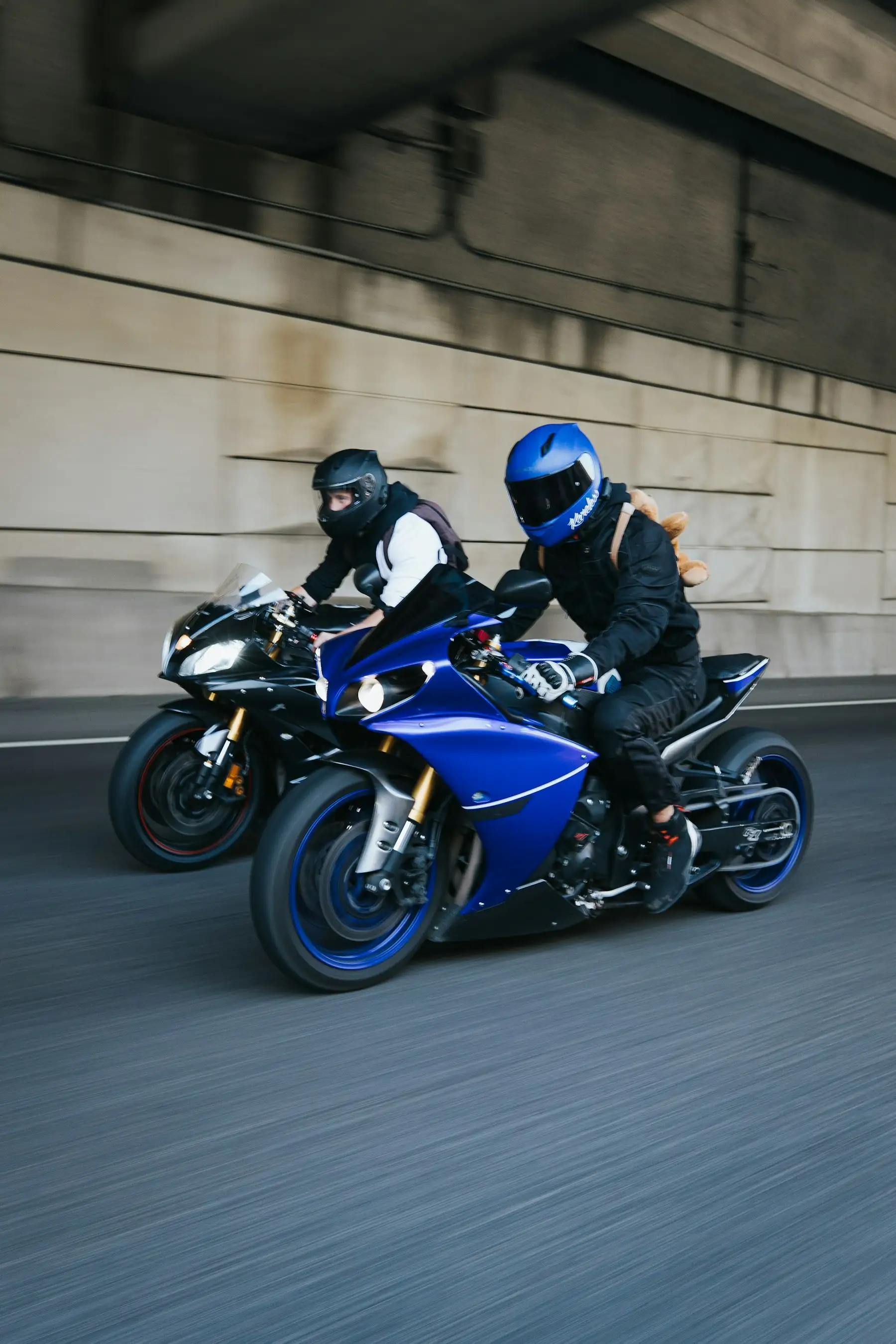 Dois motociclistas com equipamento de segurança em deslocamento por via urbana